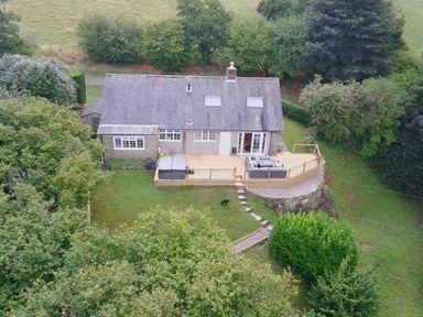 A cottage with a deck and hot tub in the garden at Hedley Dene Cottage in Longhorsley