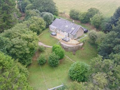 An aerial view of a house with a deck and surrounding trees at Hedley Dene Cottage in Longhorsley
