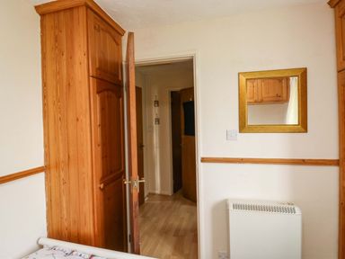 A bedroom with a wardrobe and a mirror at Cottage 28 in Brixham