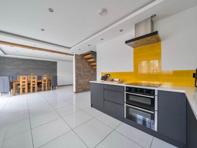 A kitchen and dining area with a staircase and kitchen appliances at The Old Barn in Abergele