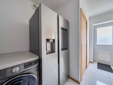 A laundry room with a refrigerator and washing machine at The Old Barn in Abergele