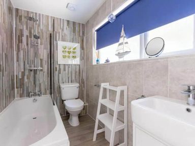 A bathroom featuring a bathtub, toilet, sink, and storage shelf at 2 Bedrooms overlooking Little Petherick Creek in Little Petherick