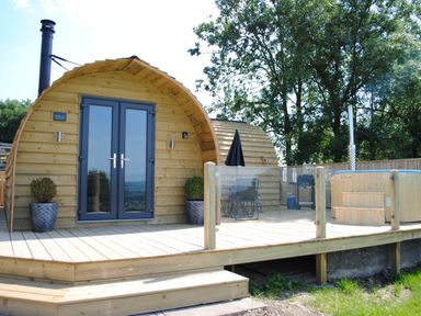A wooden structure with double doors and a hot tub at The Lodge at Brambles Farm Sleeps 4 Hot Tub in Leek
