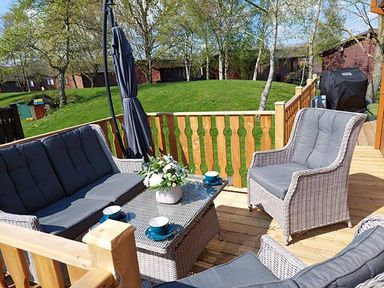 An outdoor seating area with a sofa and table at Lakeland Lodge 3Bed 2 Bath Private Patio in Carnforth