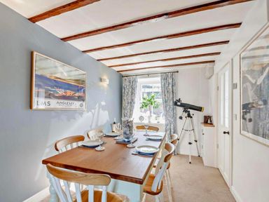 A dining room featuring a table with chairs and a telescope at Cottage Sleeps 5 with Parking and Garden, Carreglefn