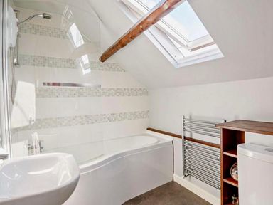 A bathroom with a bathtub, shower, wash basin, towel rail, and toilet at Cottage Sleeps 5 with Parking and Garden, Carreglefn