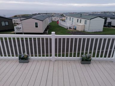 A deck with flowerpots overlooking caravans at Seaside Lodge Retreat in Eyemouth