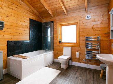 A bathroom with a bathtub, toilet, sink, and wooden features at a property