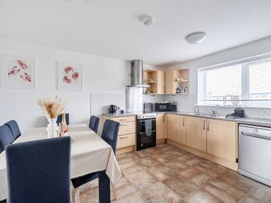 A kitchen with a dining table and appliances at Spacious 3 Bed House Sleeps 6 Parking Wifi in Newquay