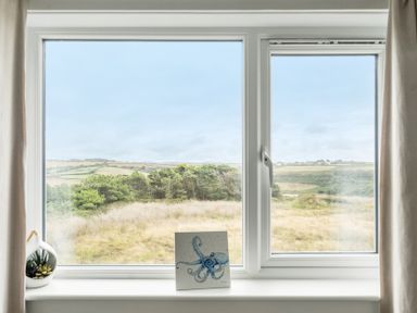 A window with a landscape view and a painting at Spacious 3 Bed House Sleeps 6 Parking Wifi in Newquay