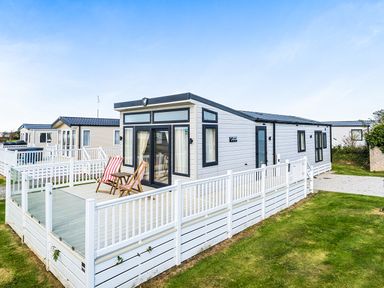 A caravan with a deck and chairs at 2Br Lodge Pool Fireplace PetsOK Parking Goonhavern