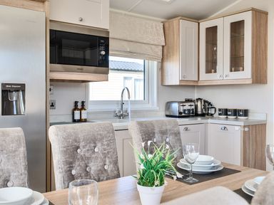 A kitchen with a refrigerator, microwave, and dining table at 2Br Lodge Pool Fireplace PetsOK Parking in Goonhavern