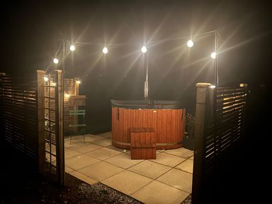 An outdoor area with a hot tub, patio and string lights