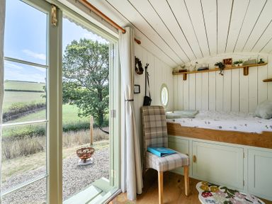 A bedroom with a bed and chair at Cosy Luxury Owls Roost Hut with Private Hot Tub near Little Deptford Farm near Umberleigh