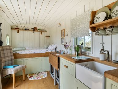 A bedroom with a bed and a kitchen area at Cosy Luxury Owls Roost Hut with Private Hot Tub, Little Deptford Farm near Umberleigh
