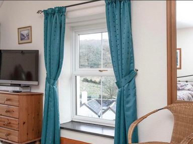 A bedroom with a window, television, and chest of drawers at The Old Barn in Manchester