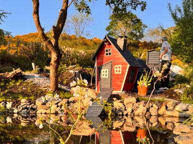 A garden with a small house and pond at The Old Barn in Manchester