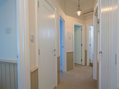A hallway with multiple doors and a light fixture at 4 The Salcombe, Salcombe