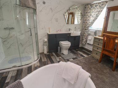 A bathroom with shower, bathtub, sink, and toilet at The Hideaway at Monterey in Helston