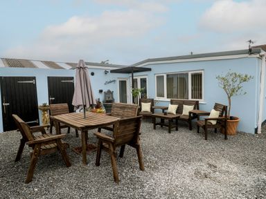 An outdoor seating area with wooden furniture at The Hideaway at Monterey in Helston