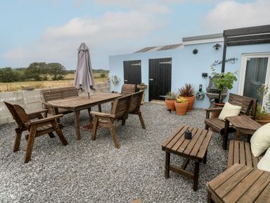 A garden with wooden furniture and planters at The Hideaway at Monterey Helston