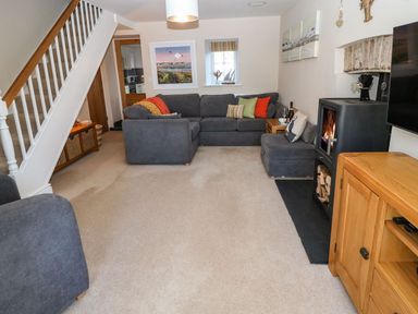 A living room with grey sofas and a fireplace at Bryn Tirion - Rhosneigr