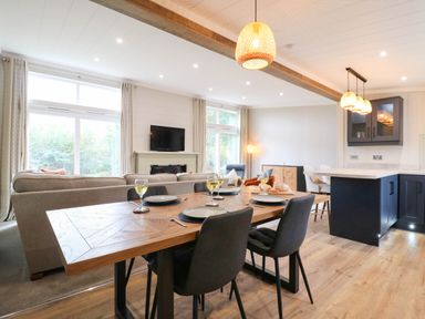 A dining table with chairs in a living room and dining area at Cherry Lodge Battisford near Stowmarket