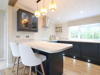 A kitchen with an island and bar stools at Cherry Lodge Battisford near Stowmarket
