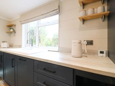 A kitchen with a sink, kettle, and window at Cherry Lodge Battisford near Stowmarket