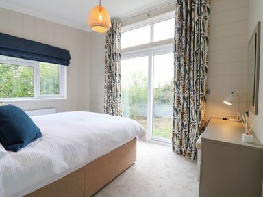 A bedroom with a bed and a window at Cherry Lodge in Battisford near Stowmarket