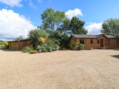 An outdoor area with two houses and greenery at Cherry Lodge Battisford near Stowmarket