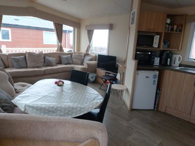 A living room with sofa and kitchen area at Golden Sands FSB38 Rhyl
