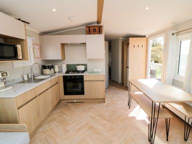 A kitchen with appliances and a dining table at 5 Rowen Court Scarborough