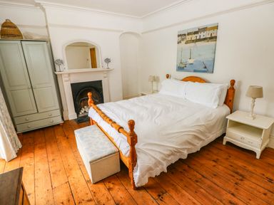 A bedroom with a bed, wardrobe, and fireplace at Y Glyn in Borth