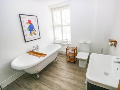 A bathroom with a bathtub, toilet, and sink at Y Glyn in Borth