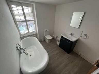A bathroom with a bathtub, toilet, and sink at Y Glyn in Borth