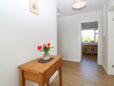 A hallway with a table and flowers at Wilpol in Llanerchymedd