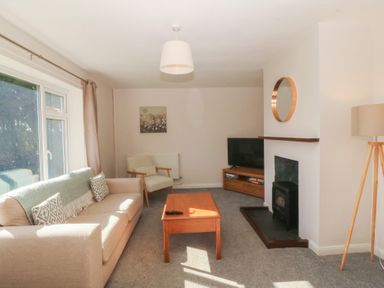 A living room with a sofa, coffee table, and television at Wilpol in Llanerchymedd