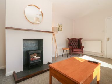 A living room with a fireplace and seating area at Wilpol in Llanerchymedd