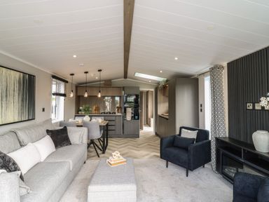 A living room with a sofa and kitchen at Lodge 8 St. Osyth
