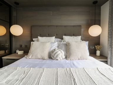 A bedroom with a bed, pillows, and lamps at Lodge 8 St. Osyth