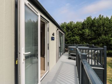A deck area with a hot tub and railing at Lodge 8 in St. Osyth