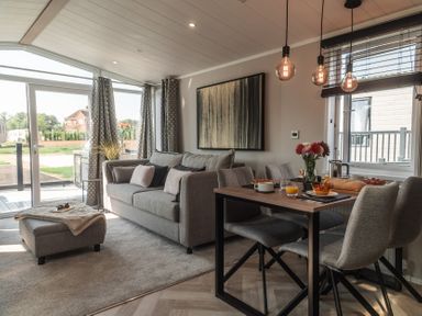 A living room with a sofa and dining table at Lakewood Plot 4 St. Osyth