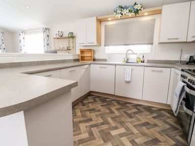 A kitchen with cabinets, sink, stove, and countertop at Rosella 38 in Morecambe