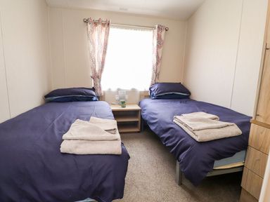 A bedroom with twin beds and a nightstand at Rosella 38 in Morecambe