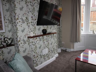 A living room with a television and decorative items at Brinkburn House in Scarborough