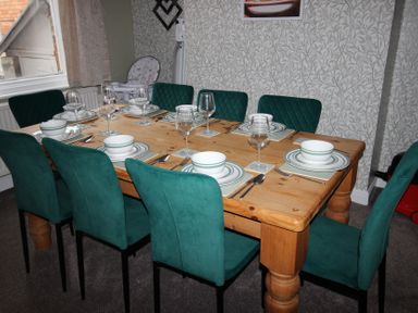 A dining room with a wooden table and green chairs at Brinkburn House in Scarborough