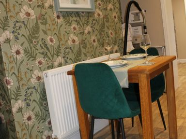 A dining table with chairs and decorative wallpaper at Blackburn Heights Apartment 1 in Bridlington