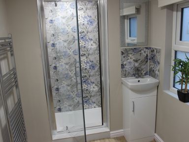 A bathroom with a shower, washbasin, and mirror at Blackburn Heights Apartment 1, Bridlington