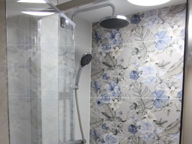 A shower with floral tiles at Blackburn Heights Apartment 1, Bridlington